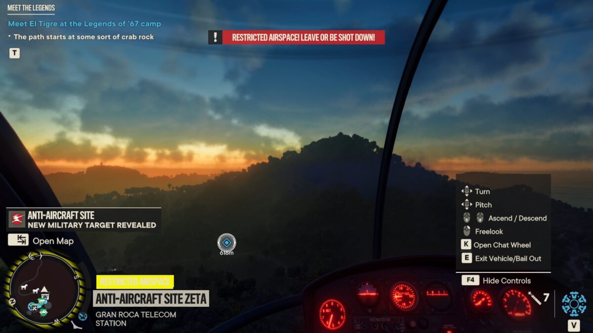 Piloting a helicopter, the destination indicator can be seen at the bottom. You can see the controls for the helicopter on the right. It’s dawn, and the sun is rising in the horizon behind a mountain.