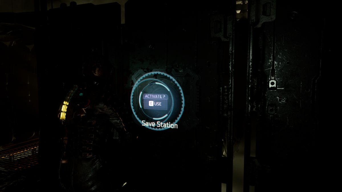 The main character in a dark room in front of a Save Station. There is a big light blue circle indicating that you can interact with the object. A text reads Activate and the prompt E Use.