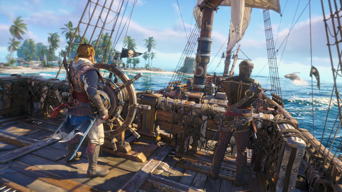 A view from behind the helm of a pirate ship sailing under a bright sky. Edward stands at the large wooden captain's wheel on the left deck, while his first mate Adewale stands to his right, looking out over a tropical ocean toward a breaching whale in the distance.